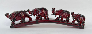 Lot 274 - Vintage red Amber carving of 4 elephants walking over incline - af 16